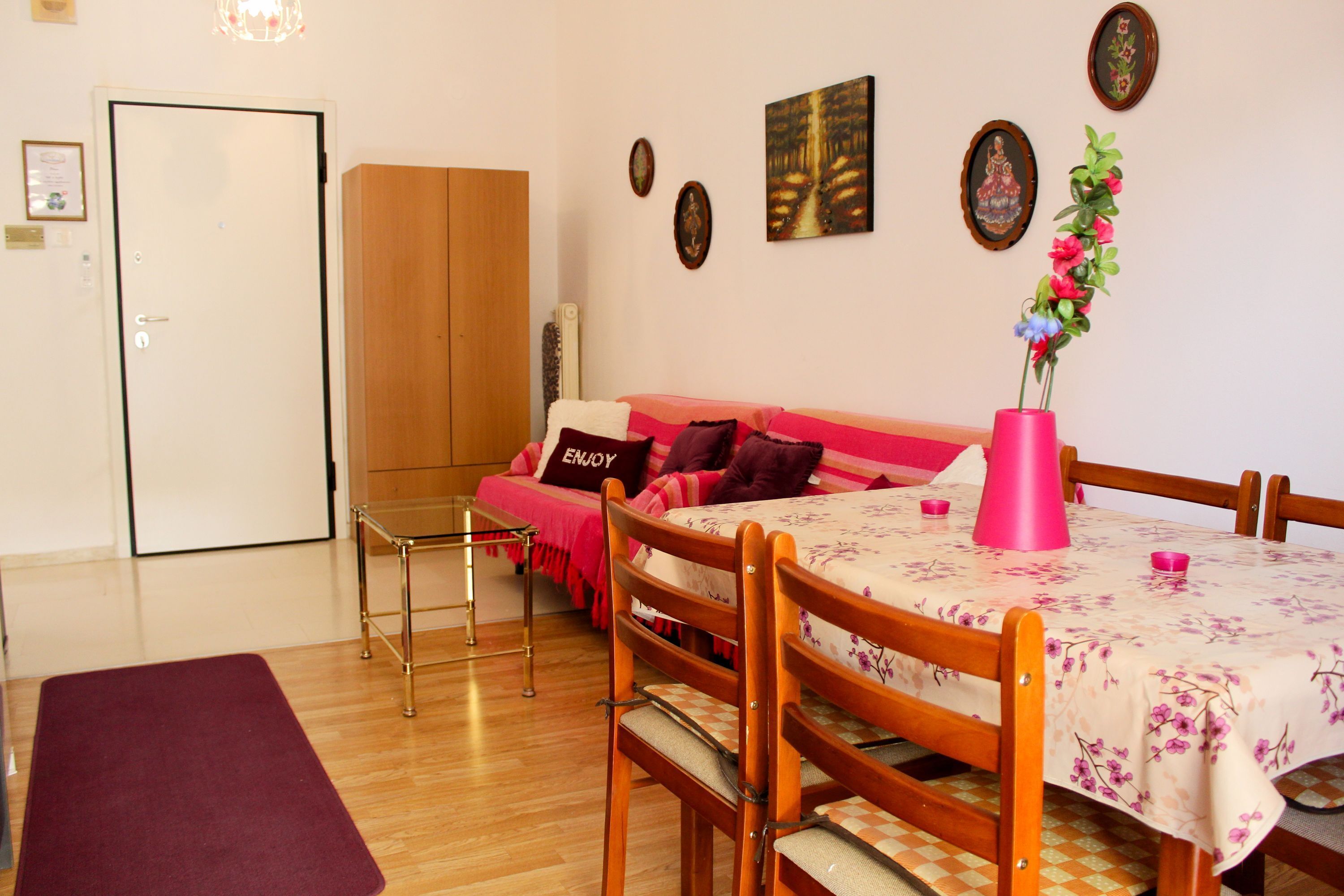A cozy room with a wooden dining table, a sofa with a floral tablecloth, and a wooden wardrobe.