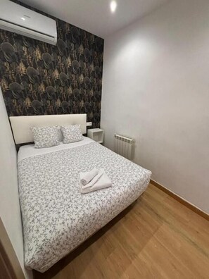 Een slaapkamer met een bed, een radiator en een wandairconditioner.