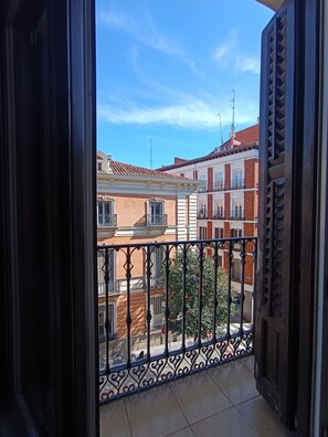 A balcony with a wrought iron railing, a tiled floor, and a view of buildings with red and white facades. - Flat55madrid (Madrid)