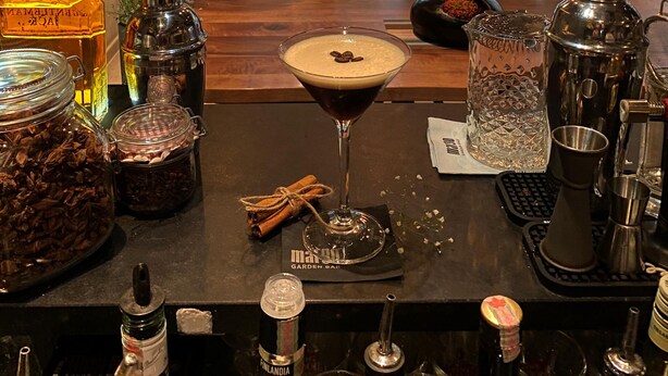 Una zona de bar con una copa de martini, varias botellas y utensilios de bar.