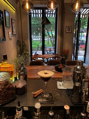 Una zona de bar con una copa de martini, varias botellas y utensilios de bar.
