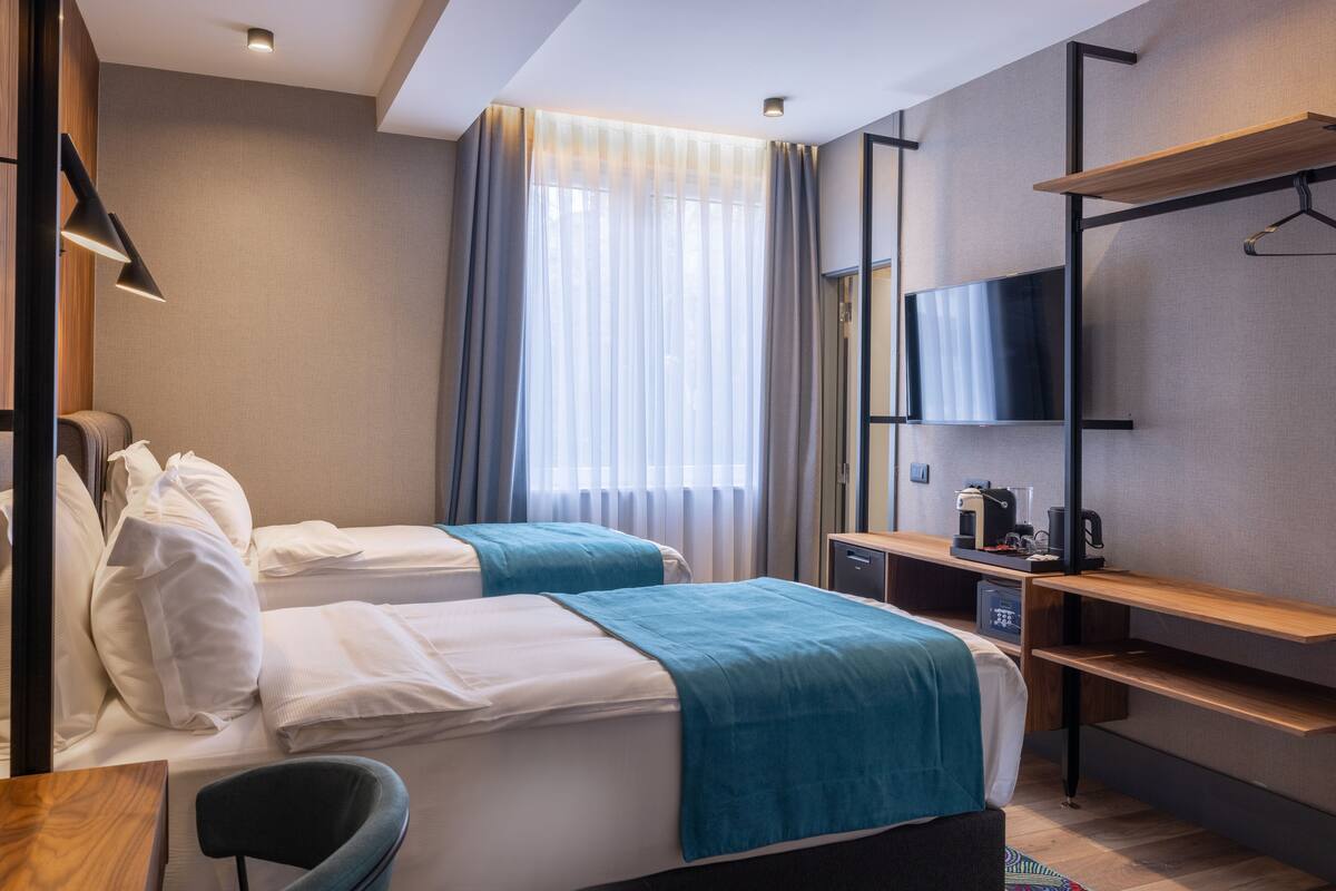 Una habitación de hotel con dos camas, un escritorio, un televisor y una cafetera.