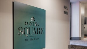 Un cartel para Hotel Square by Margo, que indica el nombre del hotel y posiblemente su ubicación dentro del edificio.