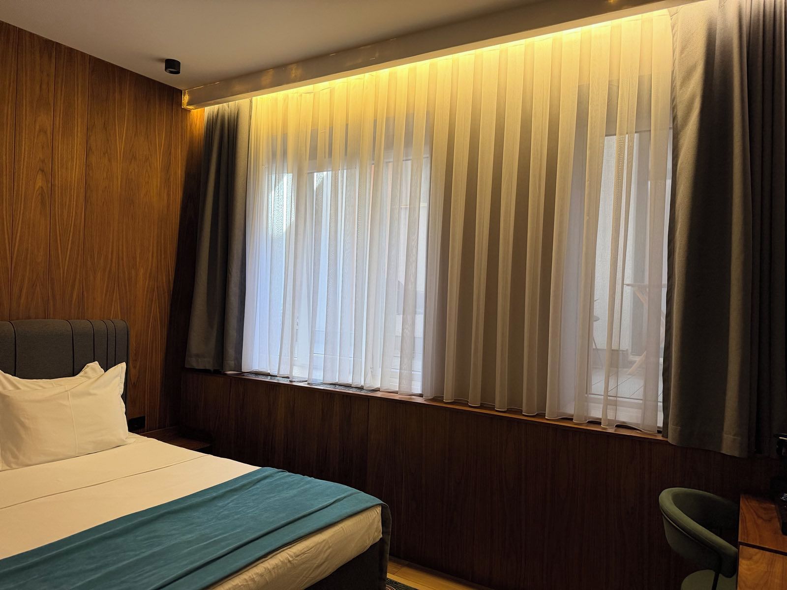 A hotel room with a bed, a desk, and a chair.
