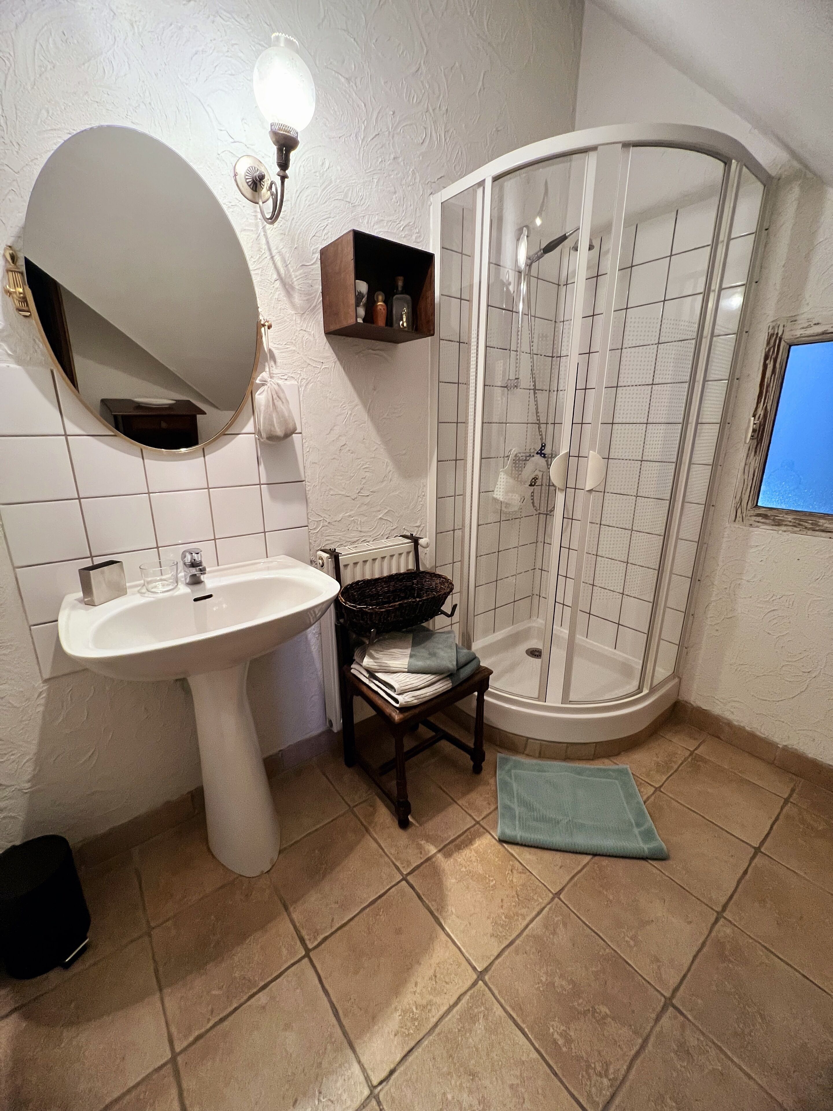 Ein Badezimmer mit Waschbecken, Spiegel, Dusche und gefliestem Boden.