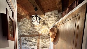 Un pasillo con pared de piedra, puerta de madera y un farol colgante.