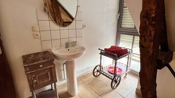 Une salle de bain avec un lavabo blanc, un miroir, un meuble en bois et une serviette rouge sur le sol.