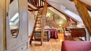 Un dormitorio acogedor en el ático con una escalera de madera, una cama, un escritorio y un aparador.