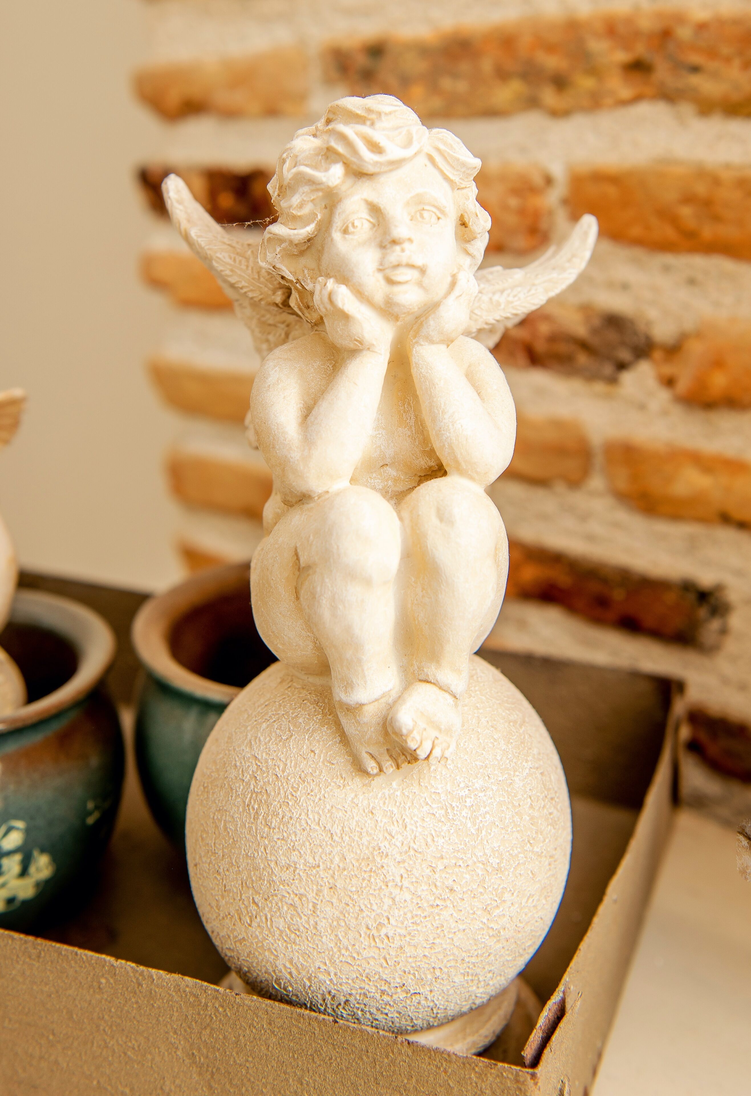 A sculpture of a cherub sitting on a spherical object.