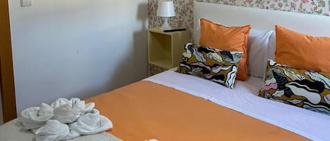 A bedroom with a bed, a nightstand, a lamp, and a floral wallpaper.