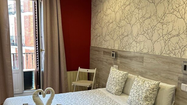 Una habitación de hotel con una cama, una silla, una mesita de noche y una pared con un diseño de árbol.