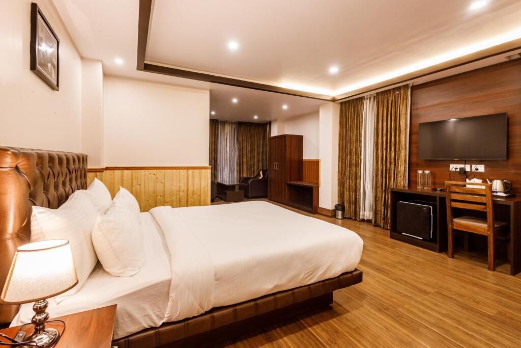 Une chambre d’hôtel avec un grand lit, un bureau avec une chaise, une télévision et une armoire.