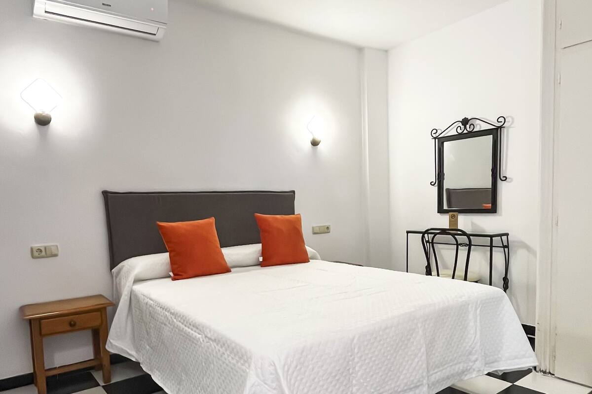 Ein Hotelzimmer mit Bett, Nachttisch, Spiegel und Klimaanlage.