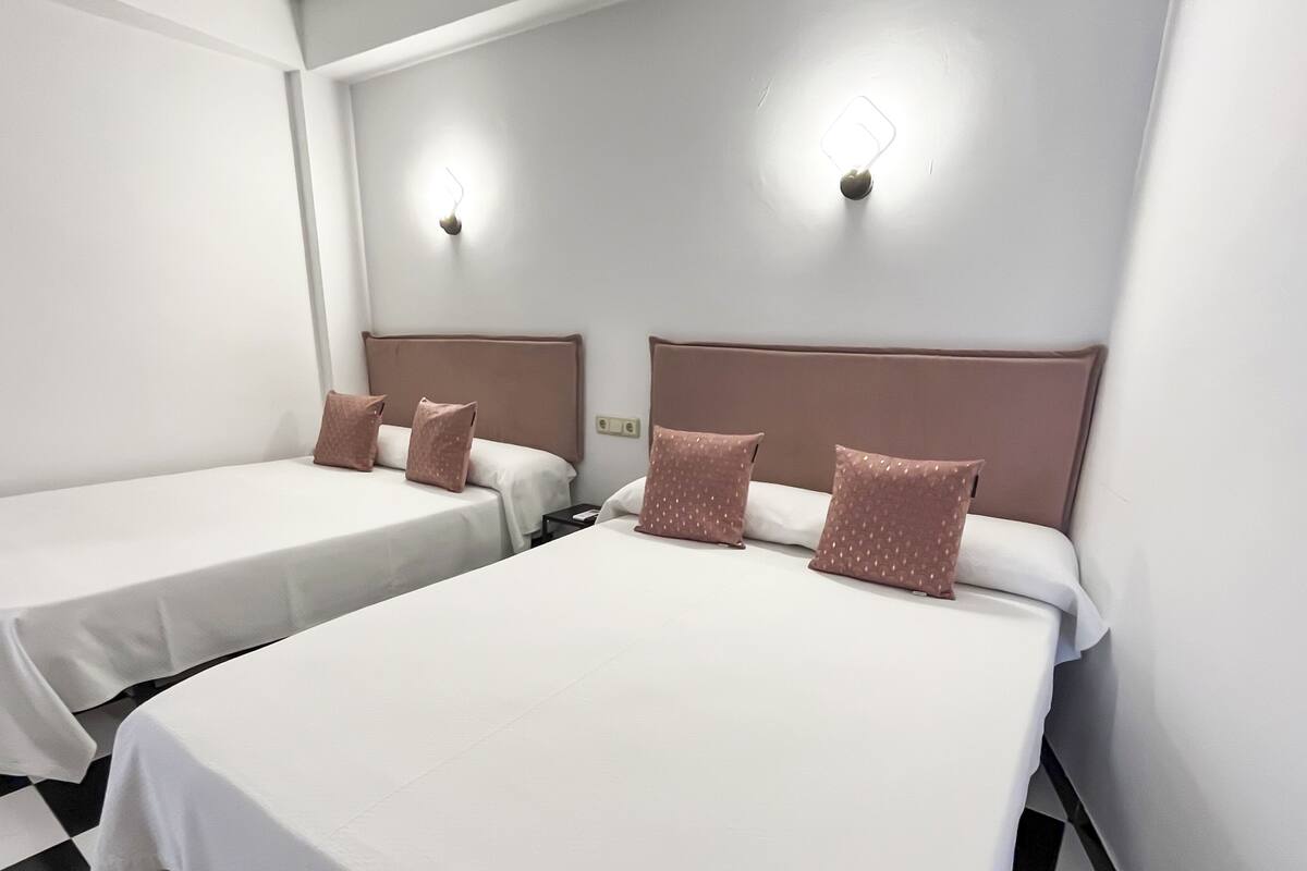 Ein Hotelzimmer mit zwei Einzelbetten, jeweils mit Kopfteil und Kissen.