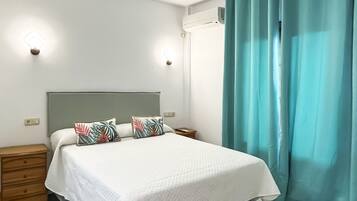 Una habitación de hotel con una cama, una mesita de noche, un aparador y un piso a cuadros.