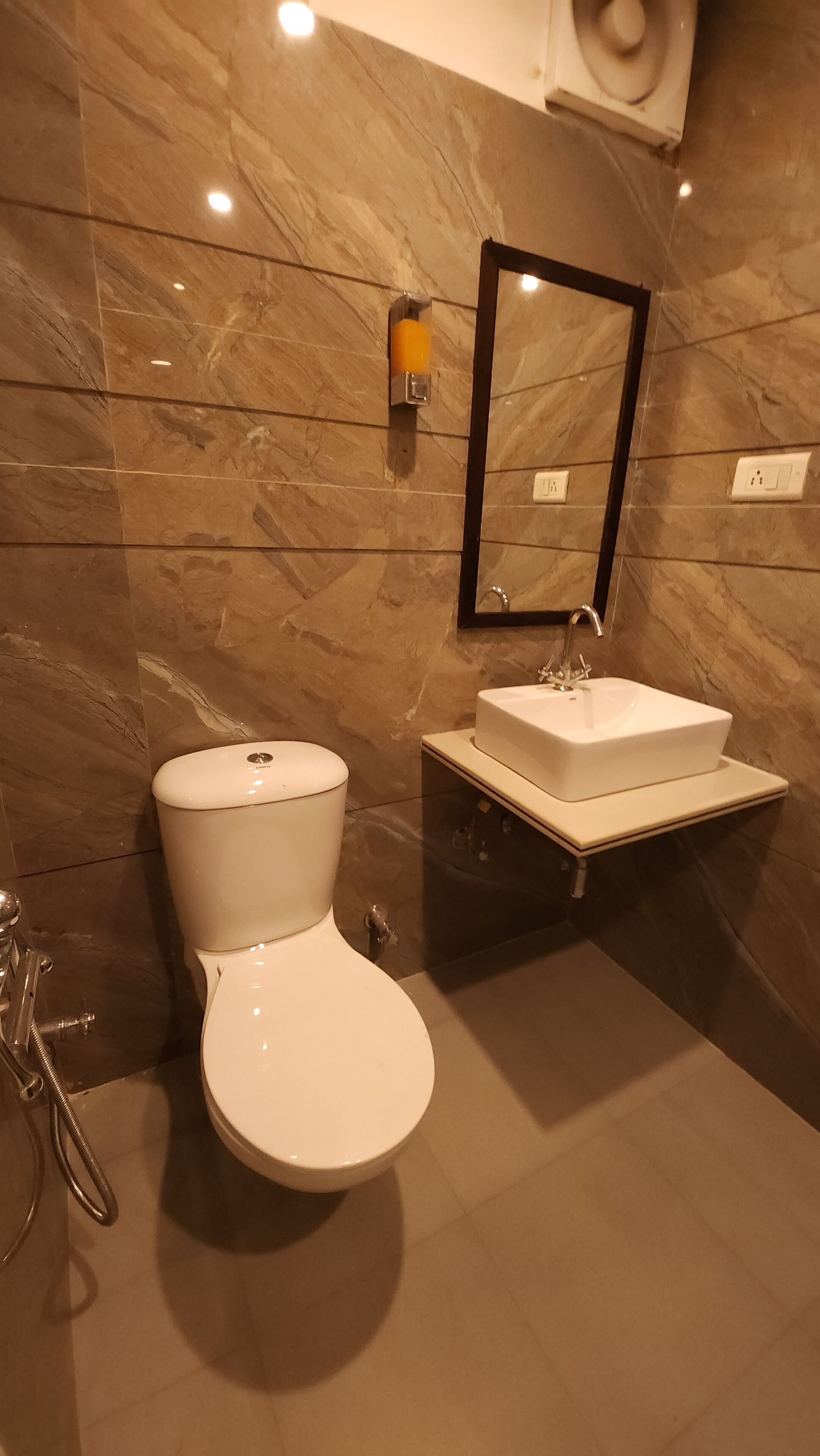 Un baño moderno con inodoro blanco, un lavabo rectangular y un espejo sobre él.
