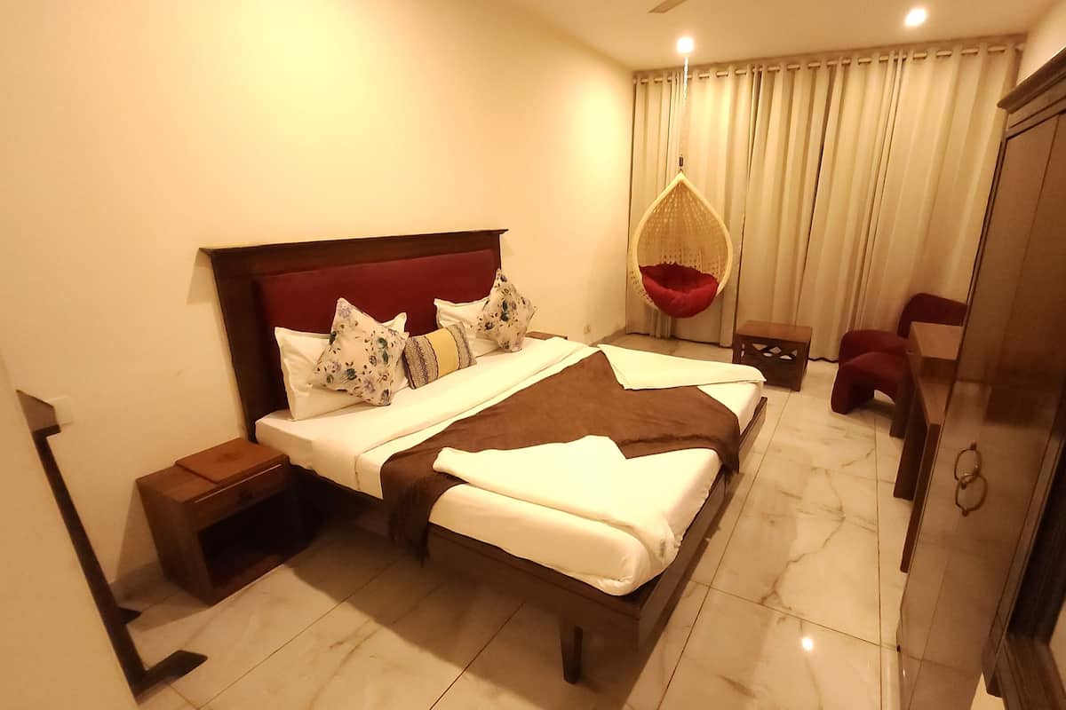 A modern hotel room with a large bed, a hanging chair, a small table, and a mirror.