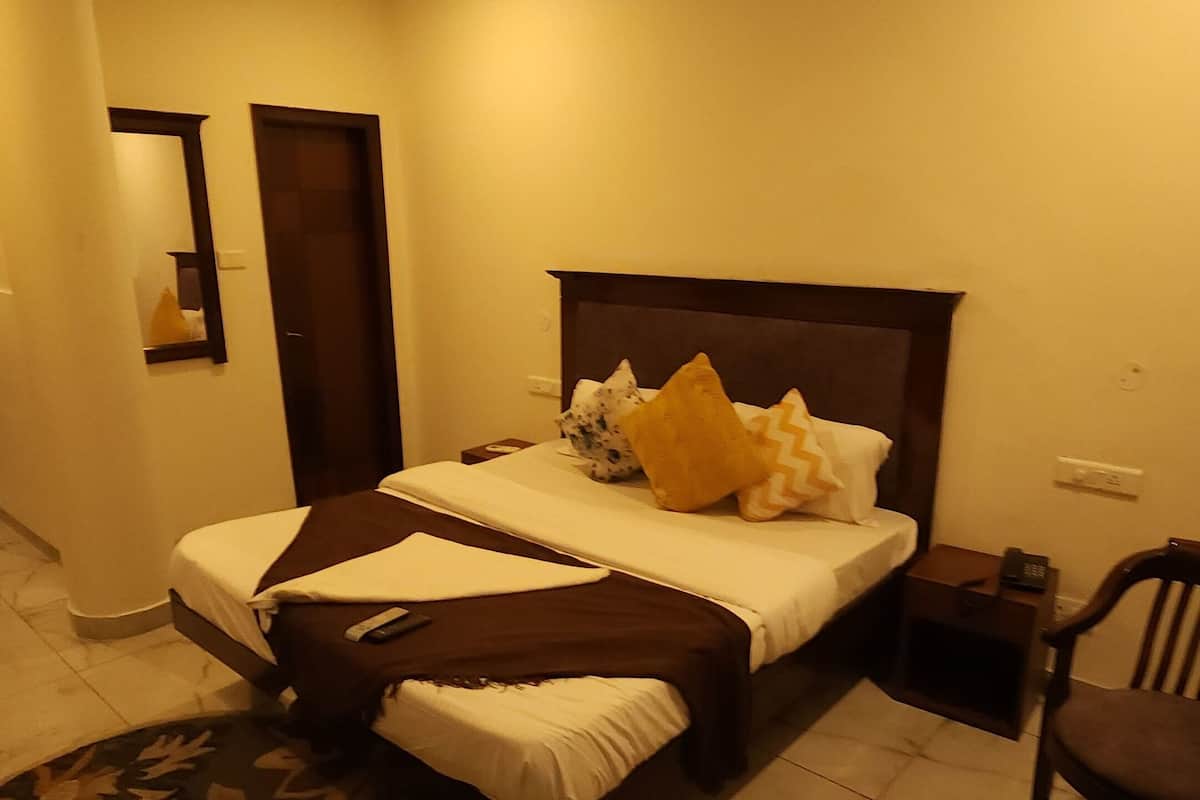 A hotel room with a bed, bedside table, chair, and a small table with a glass top.