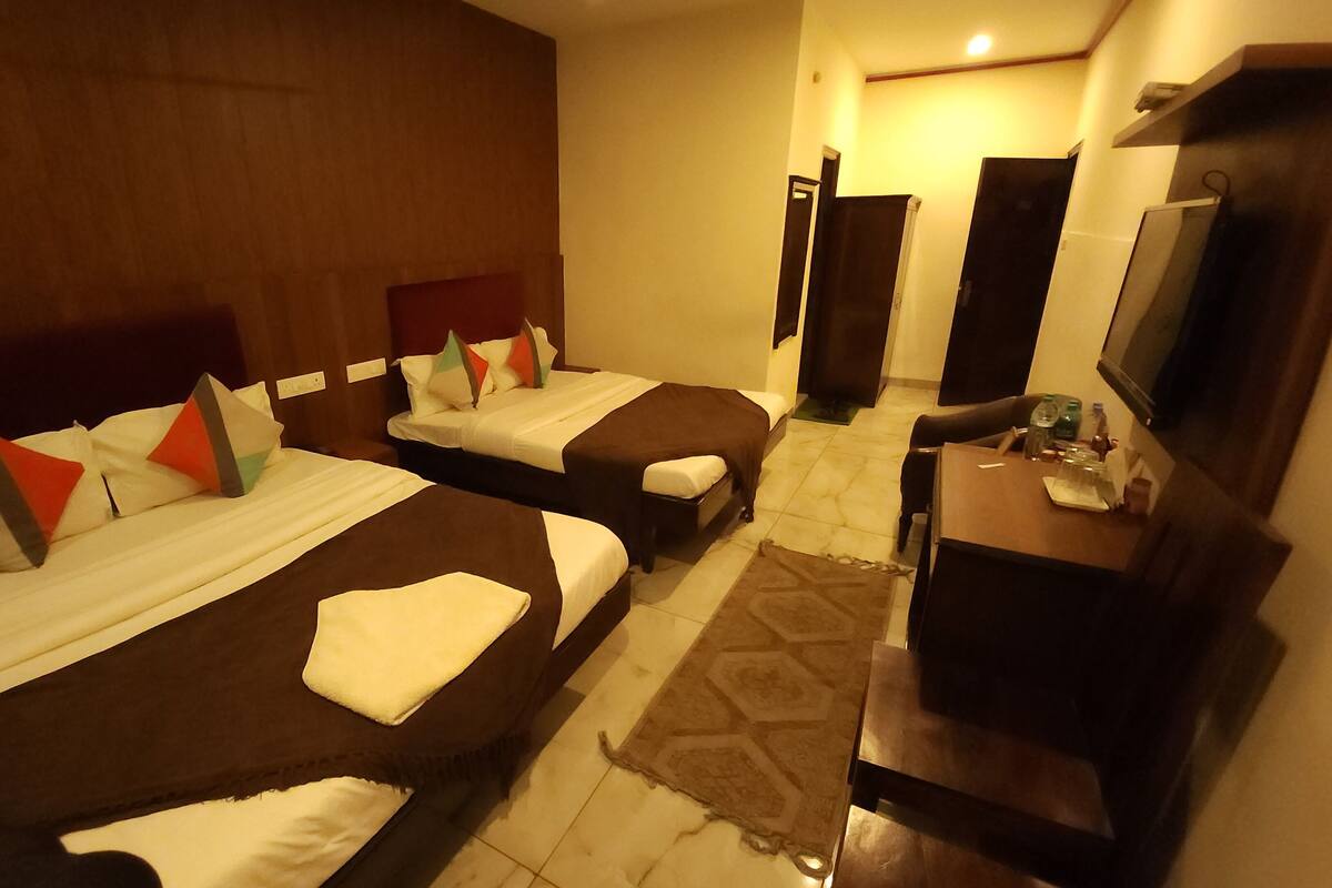 A hotel room with two beds, a TV, a desk, and a bathroom door.