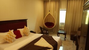 Habitación de hotel con cama, una silla colgante, una mesita, un espejo y una ventana con cortinas.