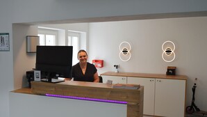 A reception desk with a flat-screen TV, a wooden counter, and a neon sign. - Boardinghaus zu Coburg (Coburg)