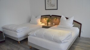 A hotel room with two single beds, a small table with a vase and a lamp, and a framed picture on the wall. - Boardinghaus zu Coburg (Coburg)