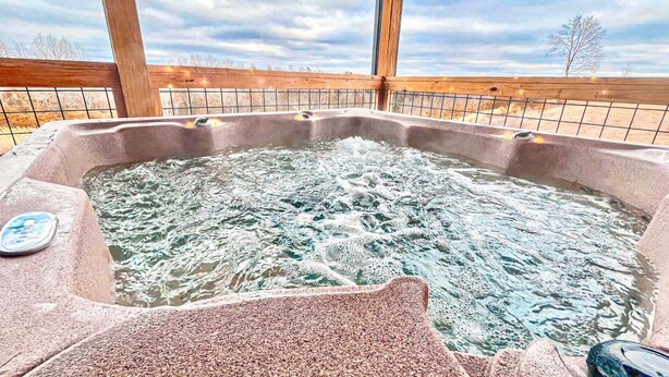 Un jacuzzi con cubierta de madera y cielo nublado al fondo.