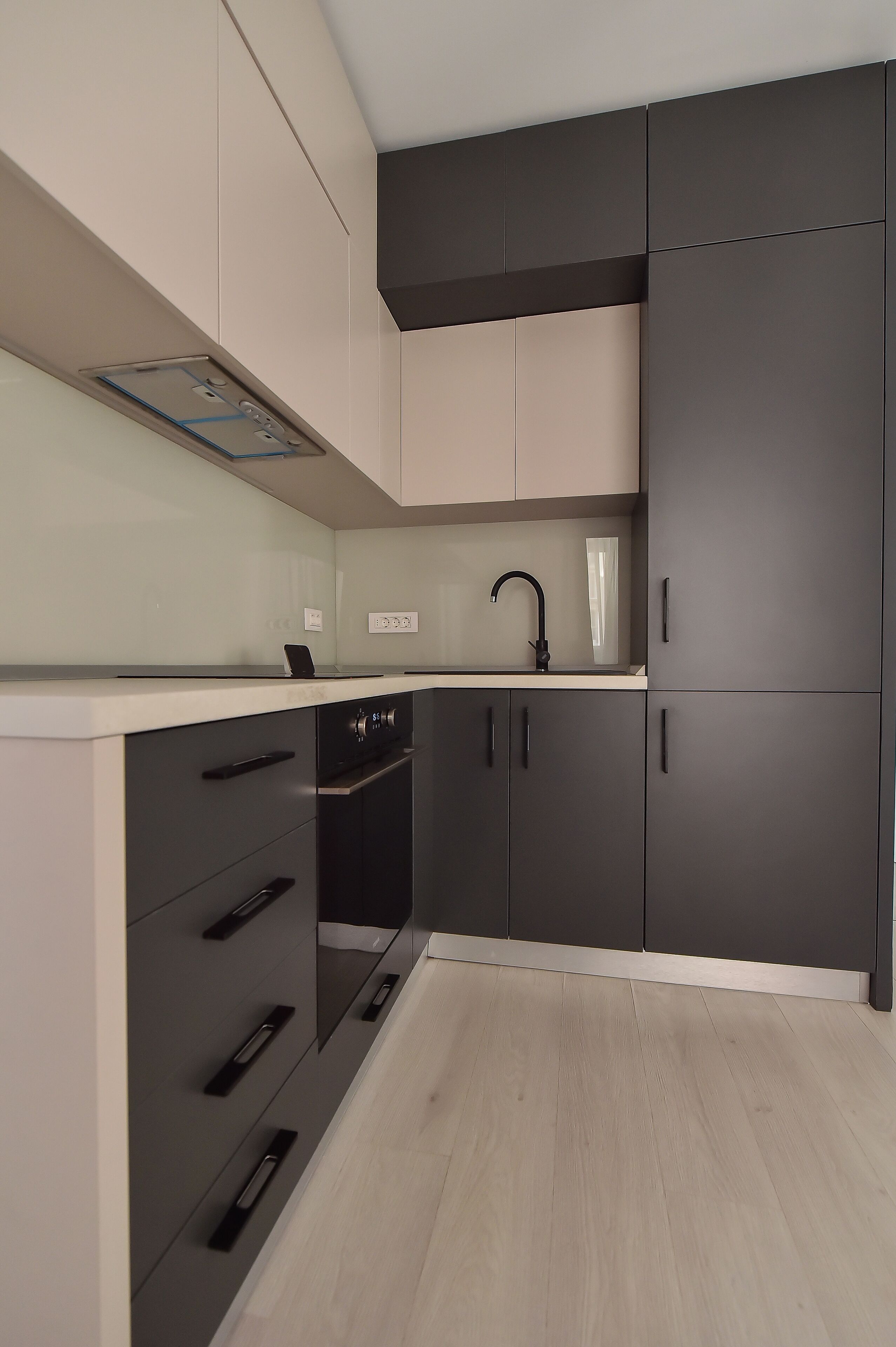 A modern kitchen with grey cabinets, a black faucet, and a light-colored countertop.