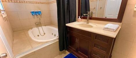 A bathroom with a bathtub, a sink, and a mirror.