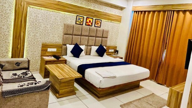 A modern bedroom with a large bed, wooden nightstands, a sofa, and a ceiling fan.