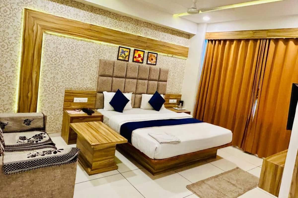 A modern bedroom with a large bed, wooden nightstands, a sofa, and a ceiling fan.