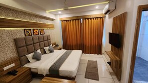 A bedroom with a large bed, a flat-screen TV, a wooden nightstand, and a small table.