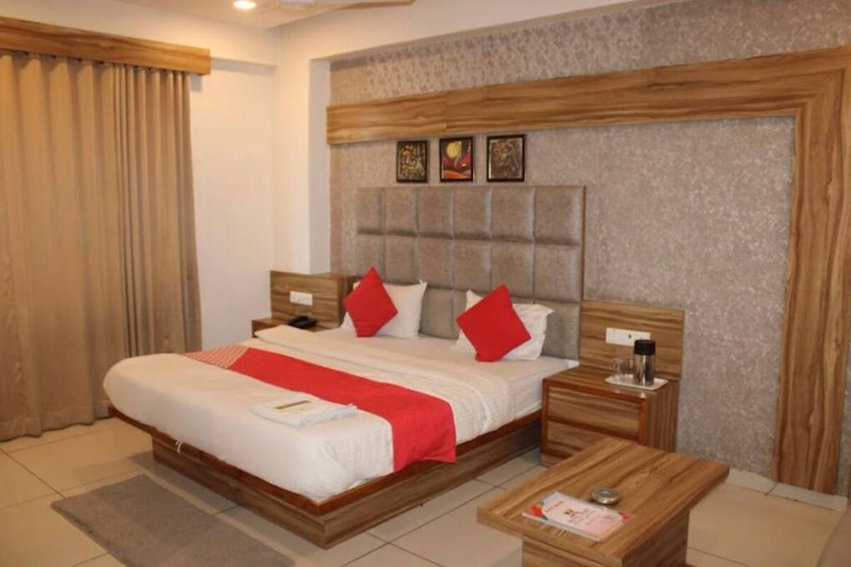 A hotel room with a large bed, wooden headboard, and a bedside table with a lamp.