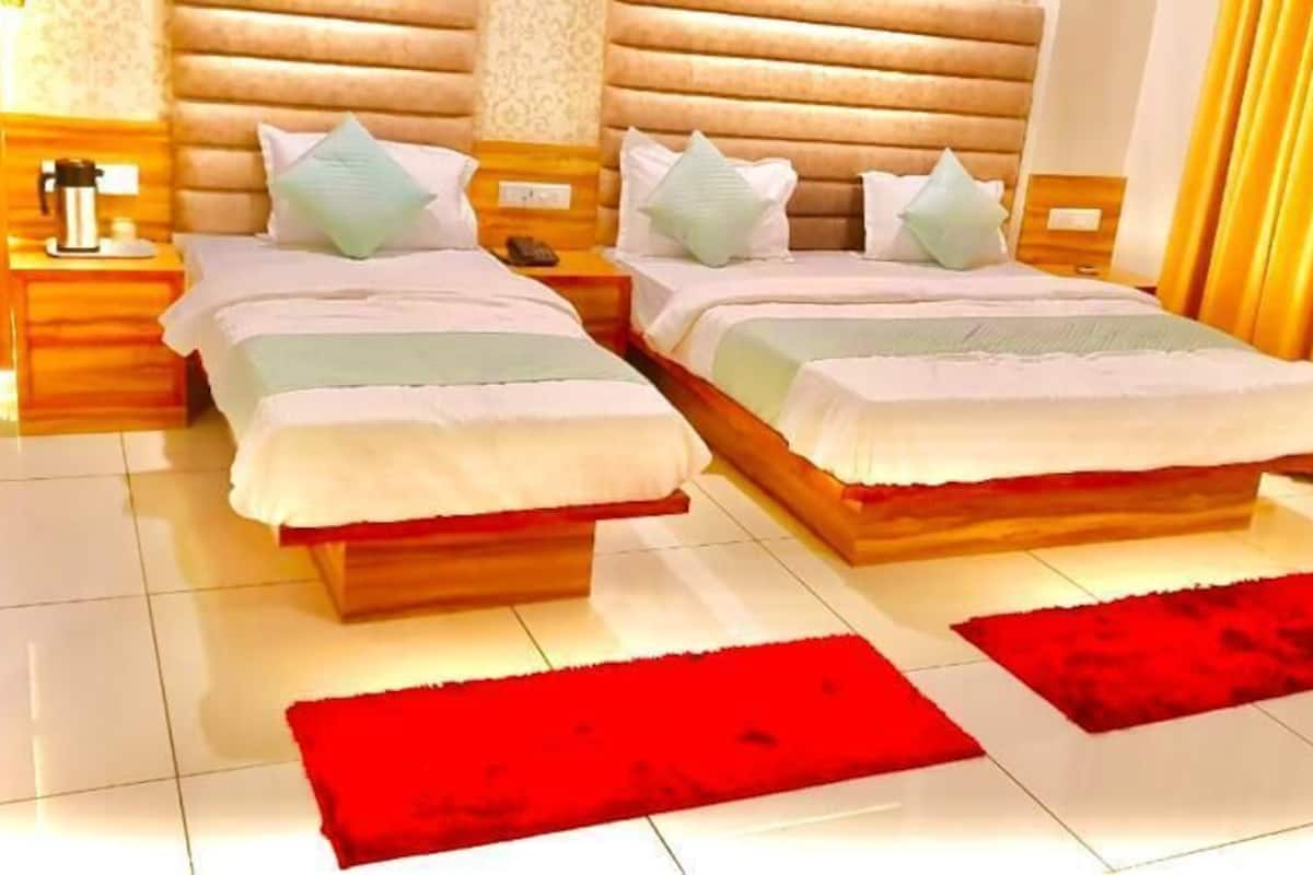 A hotel room with two beds, wooden headboards, and a red rug.