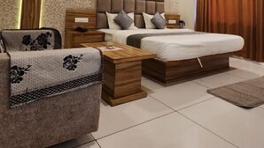 A modern bedroom with a large bed, bedside tables, a sofa, and a ceiling with linear lighting.
