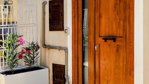 Une porte en bois avec un panneau de verre, un portail en métal blanc et un jardinier orné de fleurs roses.