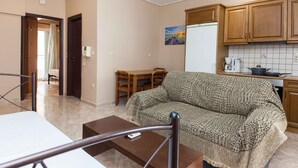 Ein Wohnzimmer mit Sofa, Esstisch und Küchenzeile mit Holzausstattung und Fliesenrückwand.
