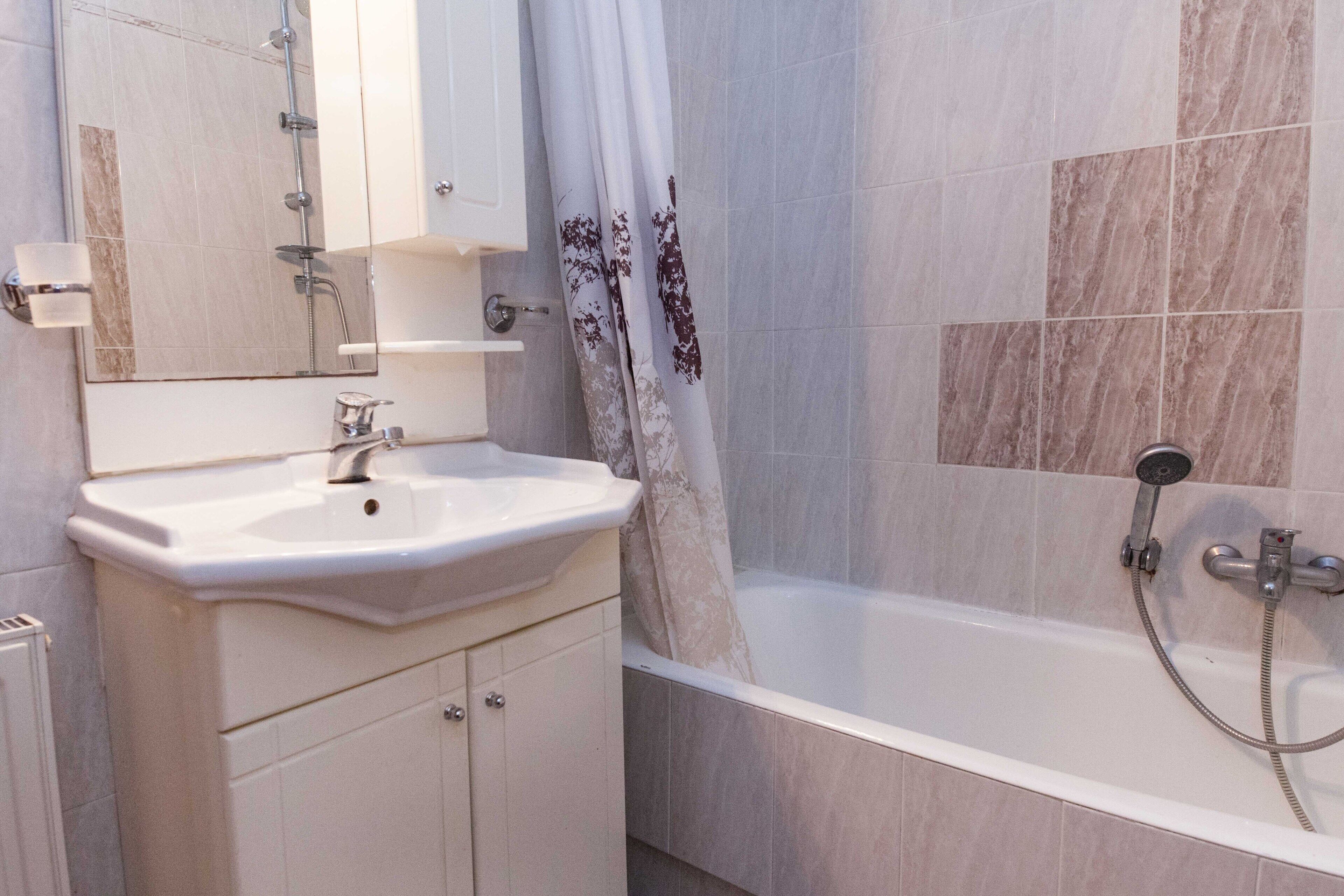 A bathroom with a white sink, mirror, and shower.