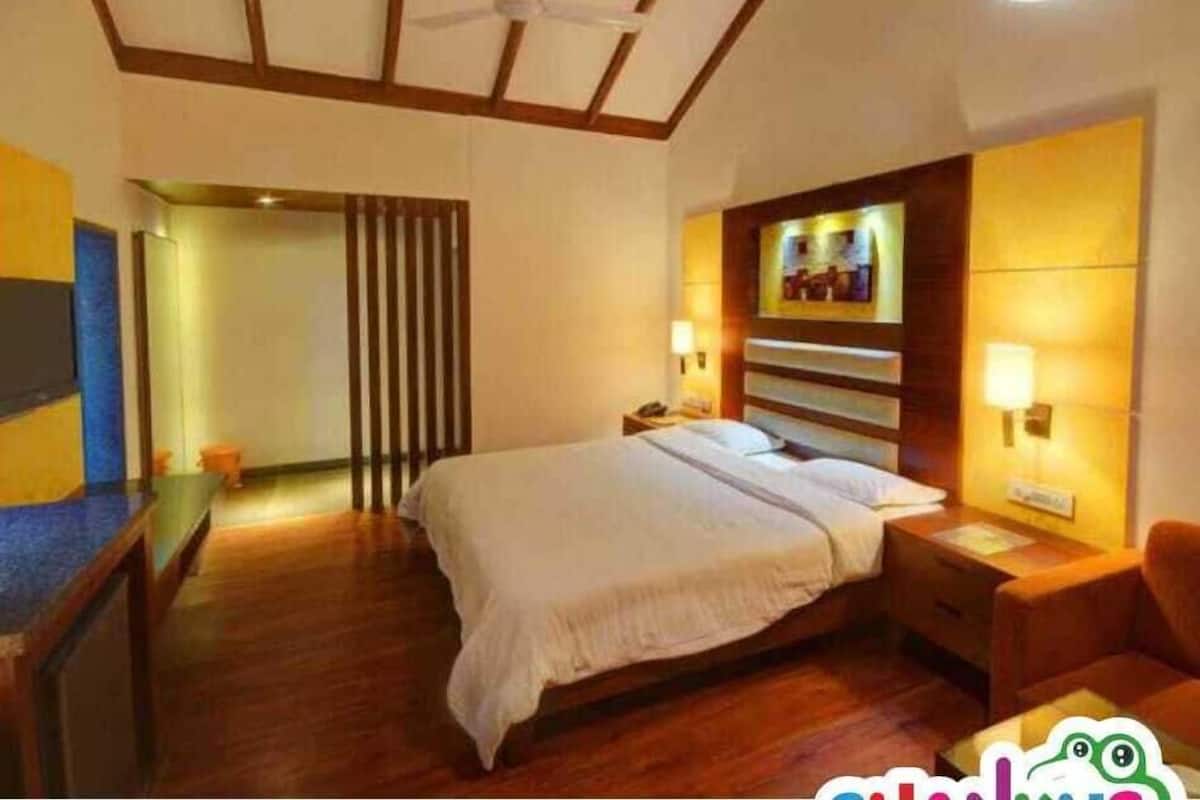 Een hotelkamer met een groot bed, een houten hoofdbord, bedlampen en een bureau met een stoel.