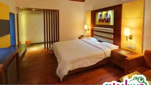 Habitación de hotel con una cama grande, cabecera de madera, lámparas de noche y un escritorio con silla.