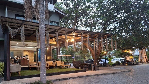 A hotel with a covered outdoor seating area, a reception desk, and a parking area. - Evergreenresort (Makham)