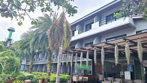 A hotel with outdoor seating, a green sign, and a modern building facade. - Evergreenresort (Makham)