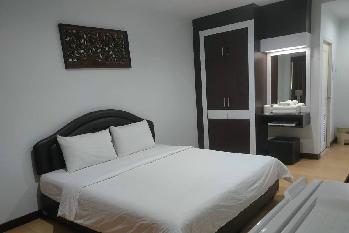 Un dormitorio con cama, armario, tocador con espejo y un adorno en la pared.