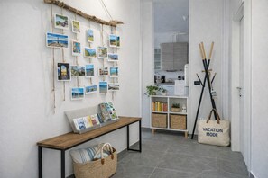 A hallway with a wooden bench, a wall adorned with travel photos, a small bookshelf, and a 'VACATION MODE' tote bag. - Lago Maggiore holiday house (Dumenza)