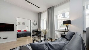 Ein modernes Wohnzimmer mit einer Couch, einem Couchtisch, einem Fernseher und einem Schreibtisch mit Stuhl.