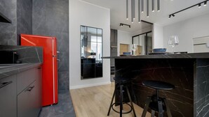 Eine moderne Küche mit einem roten Kühlschrank, schwarzen Marmorarbeitsplatten und einer Bar mit Barhocker.