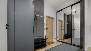 Ein modernes, minimalistisches Zimmer mit grauen Schränken, einer Bank und einem großen Spiegel.
