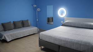 Ein Zimmer mit einem Bett, einer Couch, einem Spiegel und einer Wandleuchte.