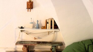 Accogliente camera mansardata con una panca di legno, un pouf verde e uno scaffale con libri e oggetti decorativi.