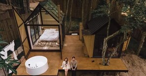 A treehouse with a bed, a hot tub, and a wooden deck. - Morning Star Glamping (Mae On)